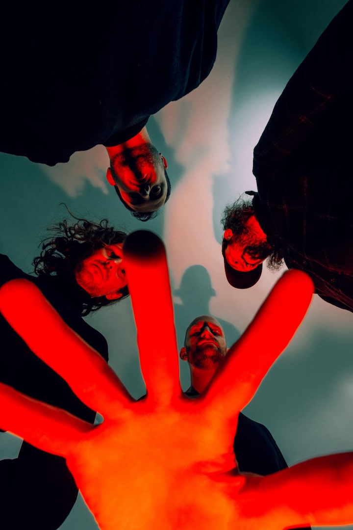 UNTITLED WITH DRUMS shot from below with a red-lit hand over the lens