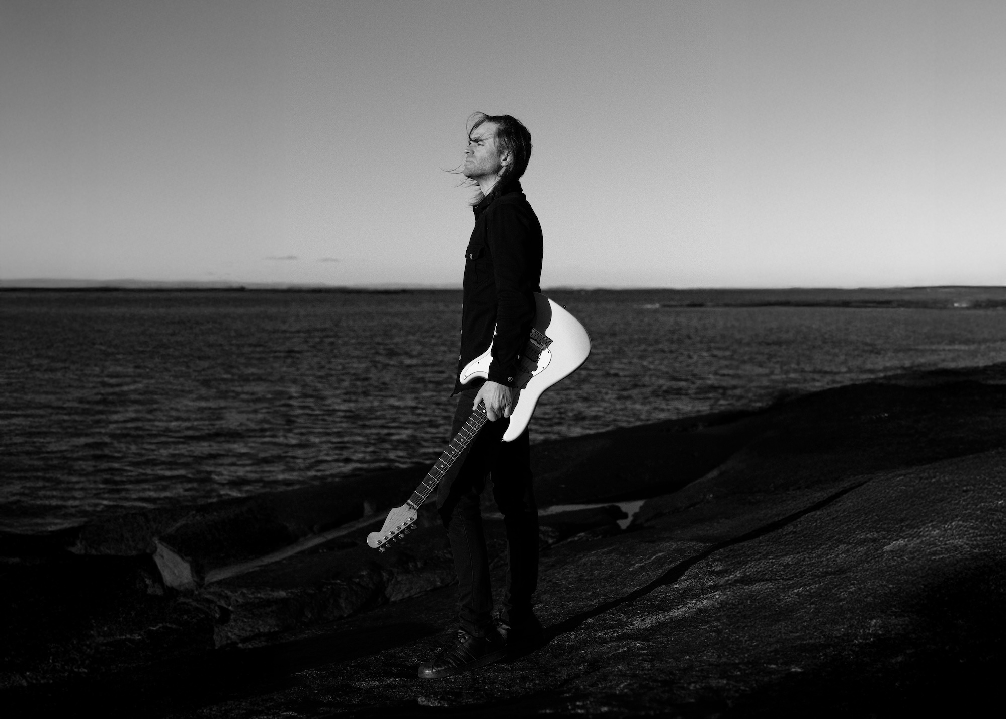 Gildas Le Pape of VIA DOLORIS holding a guitar by the sea